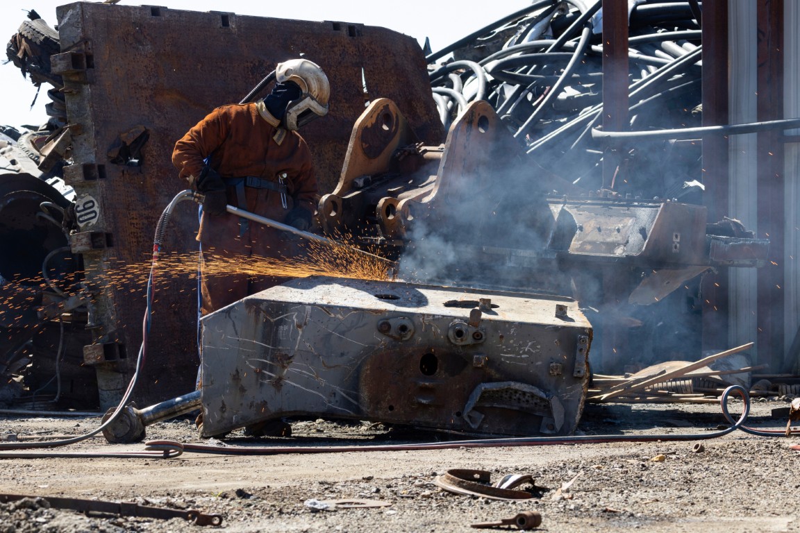 Gros plan sur un chalumiste coupant un bloc d’acier au chalumeau, étincelles et fumées visibles