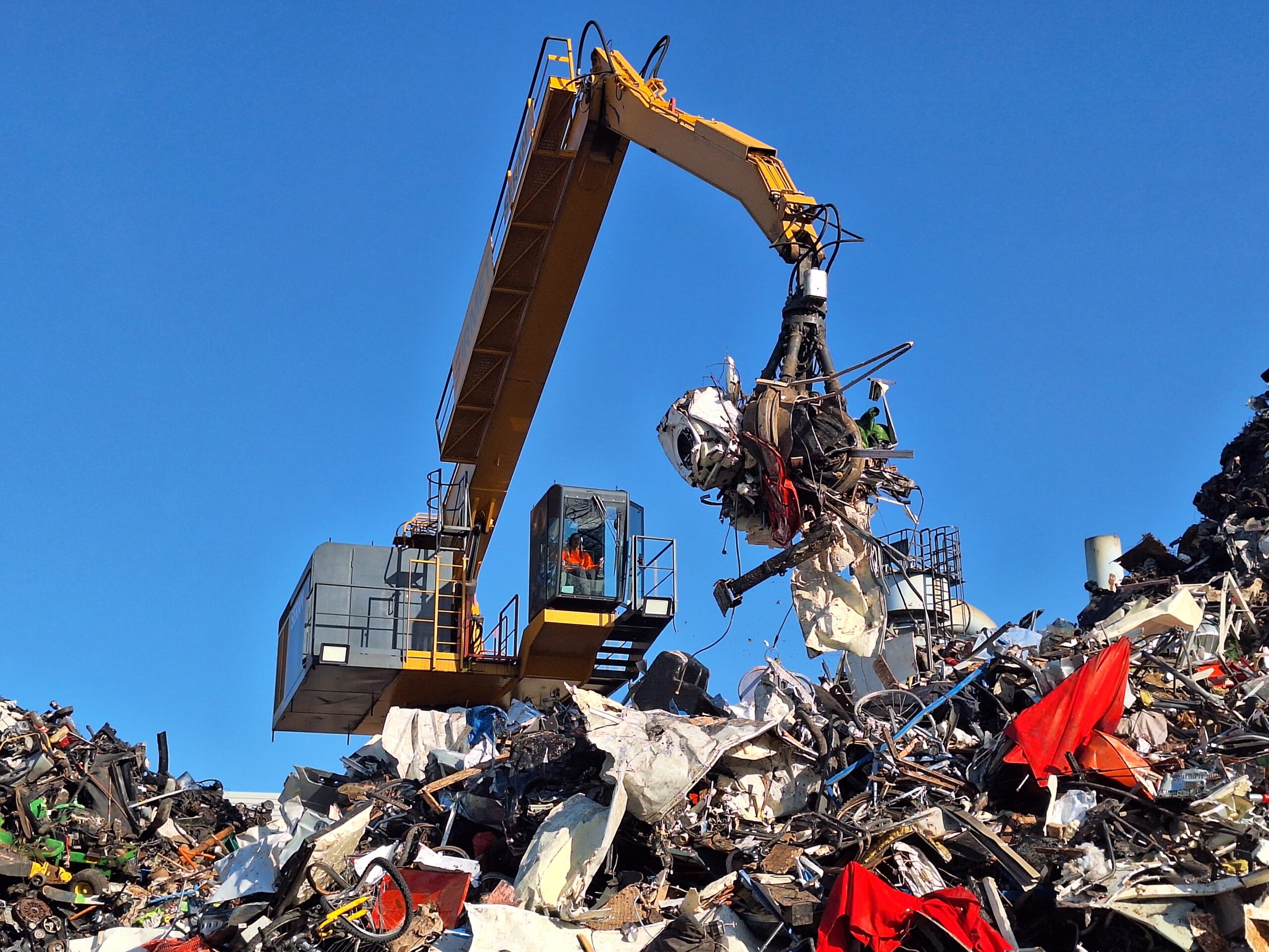 Grappin hydraulique extrayant un lot de ferrailles et d’objets divers depuis une cabine surélevée