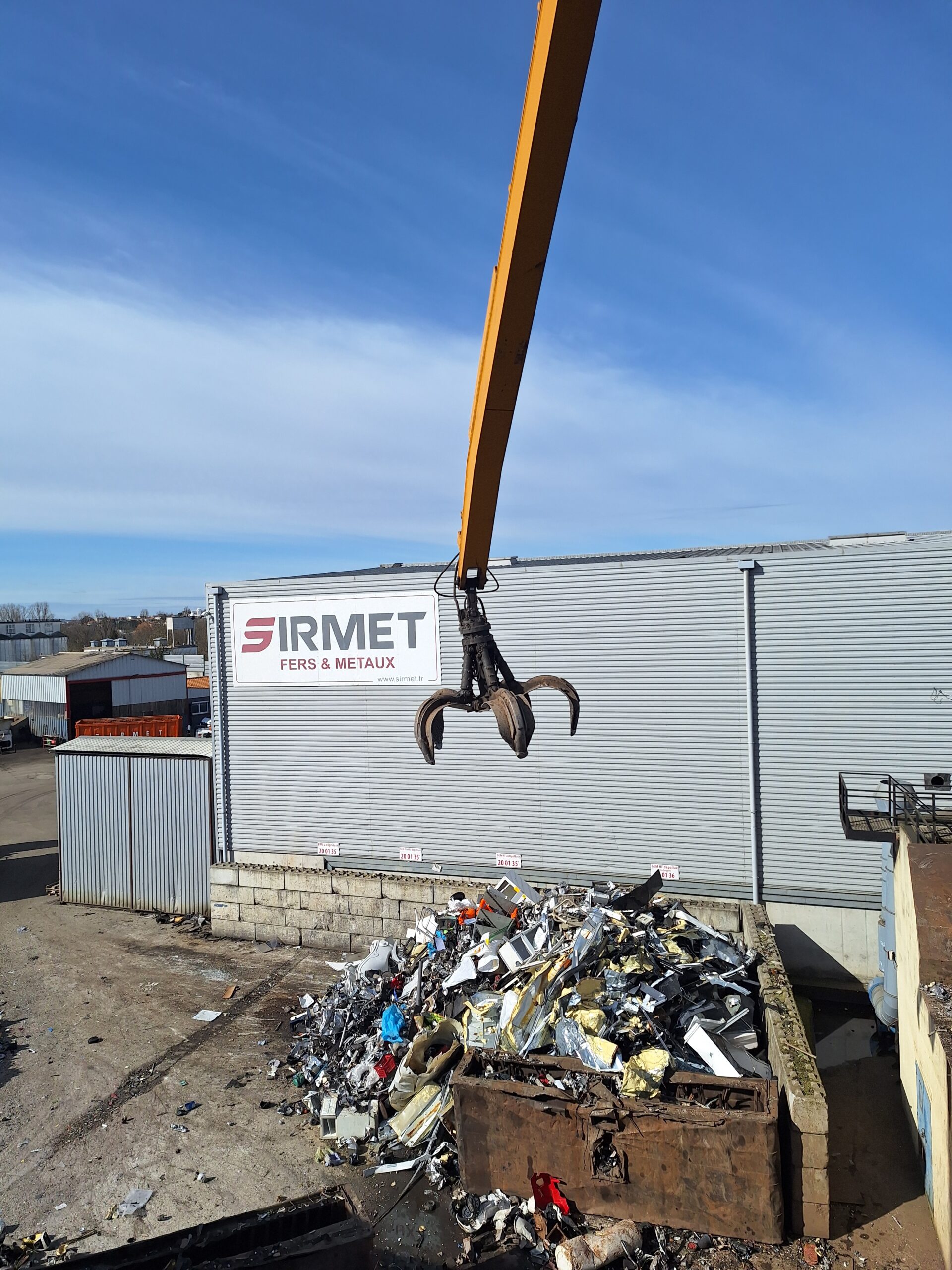 Grappin de manutention sur bras SERAM au-dessus d’un tas de ferrailles, sur parc SIRMET