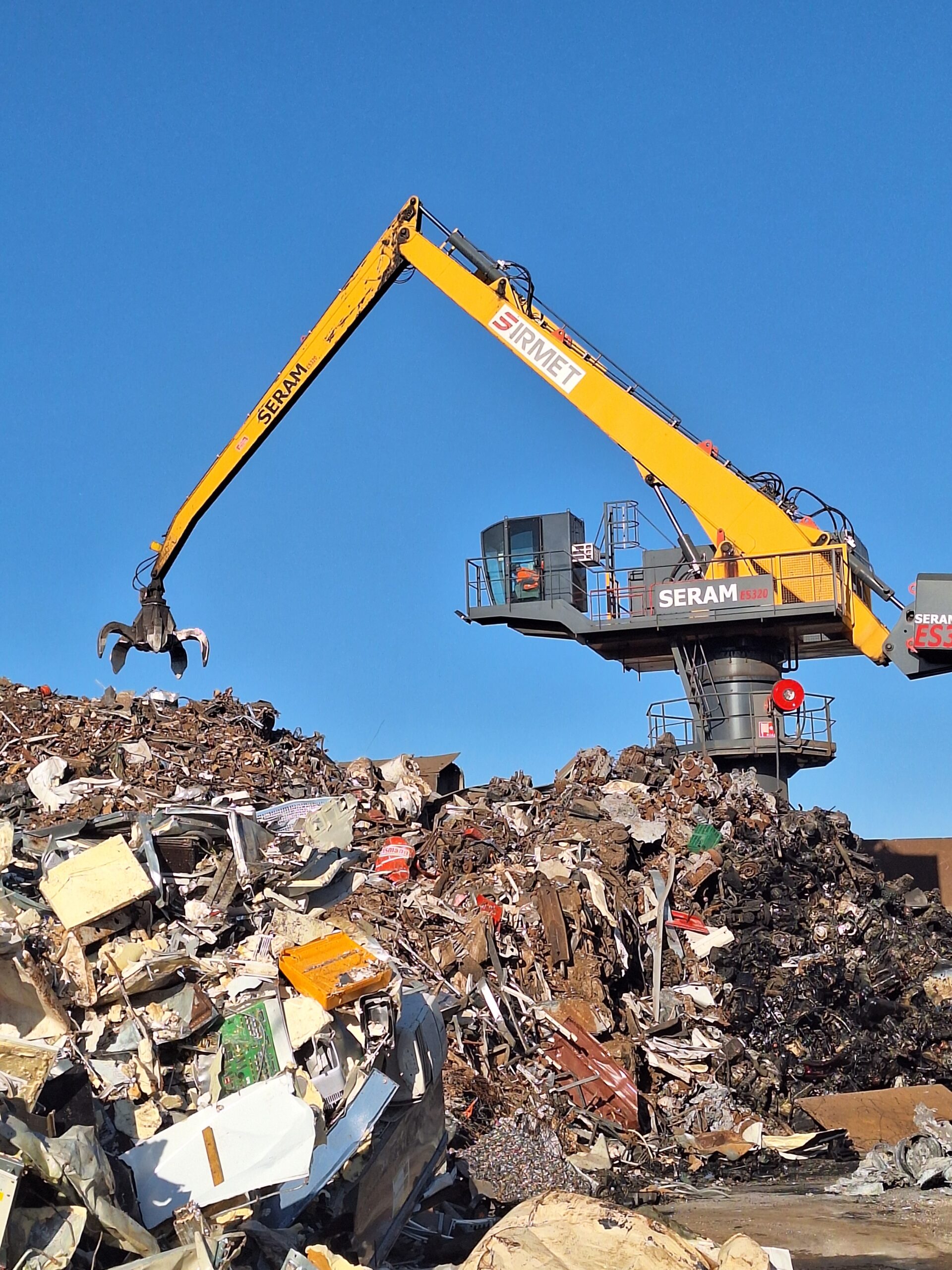 Conducteur de pelle à roues maniant un grappin pour trier la ferraille en plateforme de recyclage
