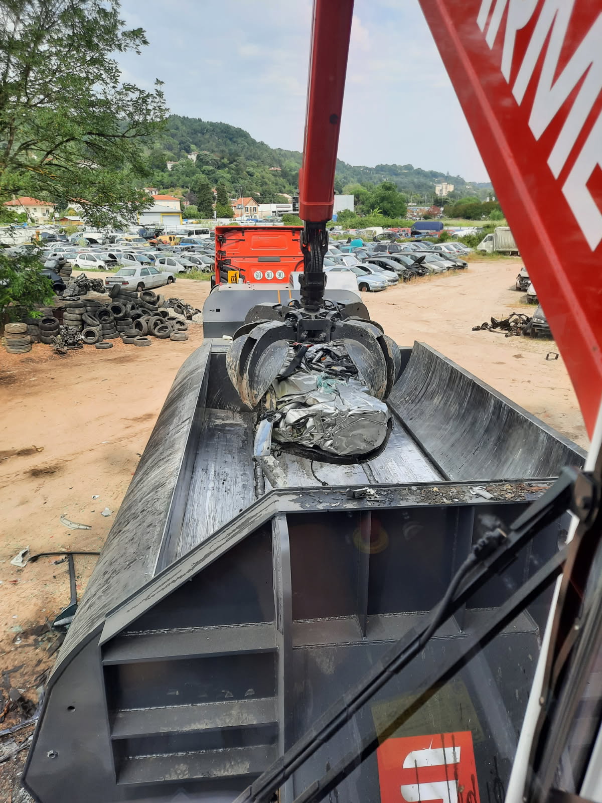 Chalumiste découpant une pièce métallique sur une plateforme de recyclage, avec grue et tas de ferrailles en arrière-plan